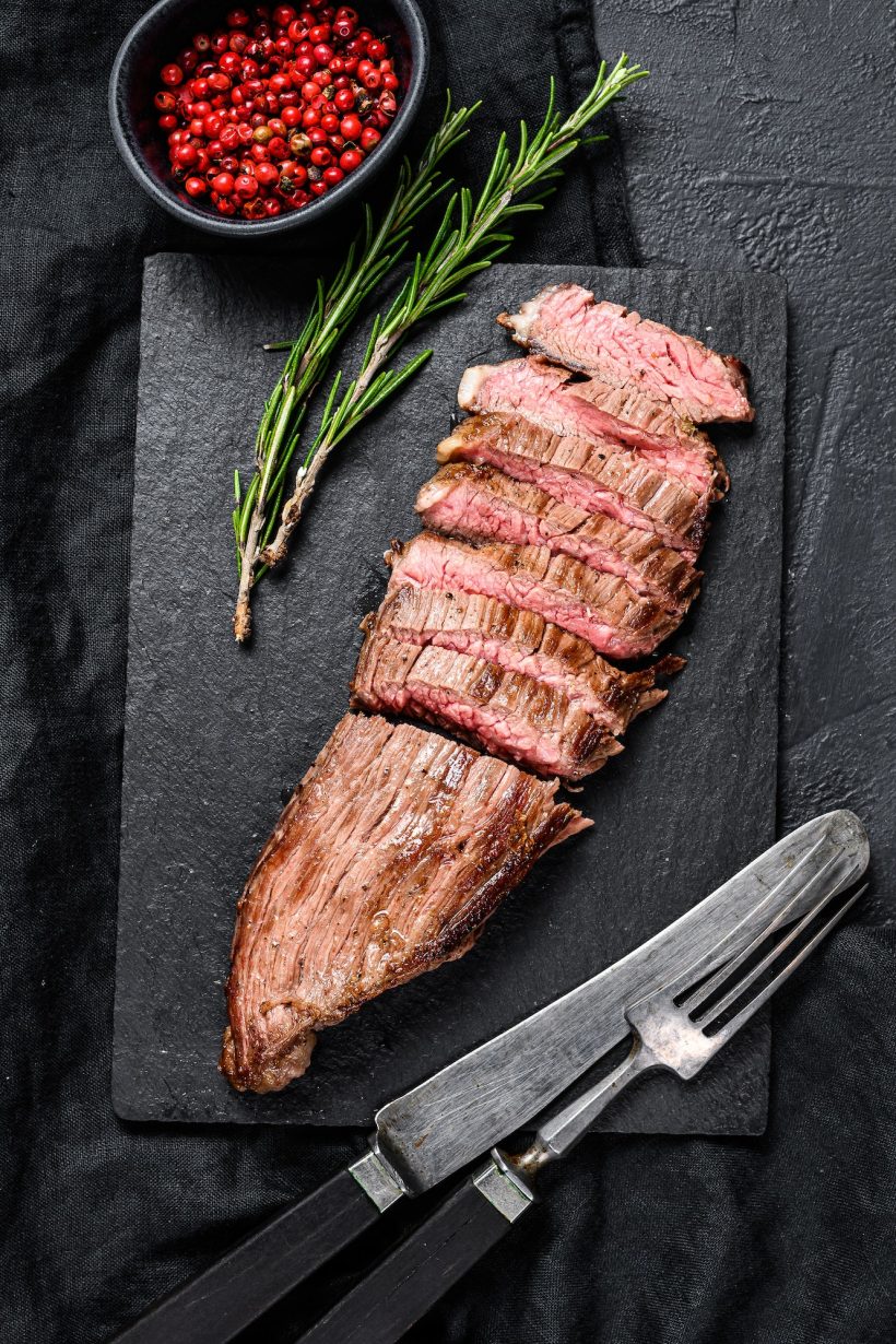 grill-restaurant-beef-menu-flank-steak-on-a-black-stone-board-black-background-top-view.jpg